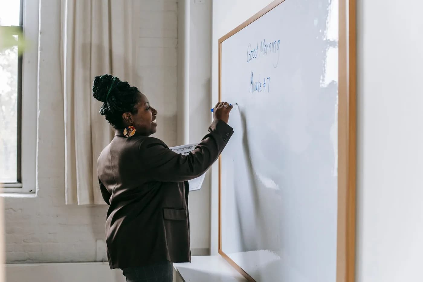Cheerful teacher writing on a classroom whiteboard